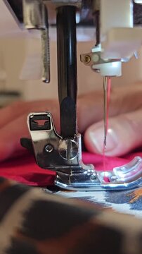 Sewing red teddy fleece and leopard print fabric on white machine close up