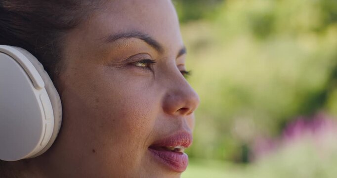 Female wearing white over-ear headphones music playing opening eyes smiling gazing into garden