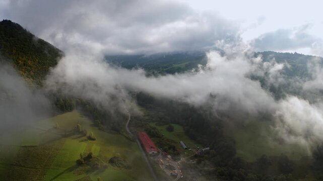 Aerial orbit scenery of mountains with morning mist and farm buildings