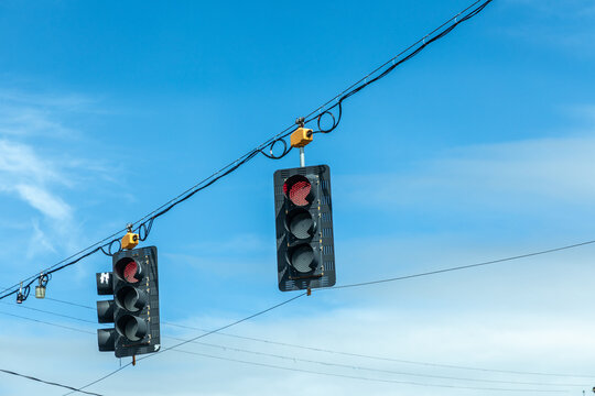 traffic lights in black and yellow hanging at a crossing with red stop light on