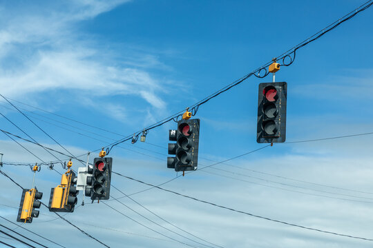 traffic lights in black and yellow hanging at a crossing with red stop light on