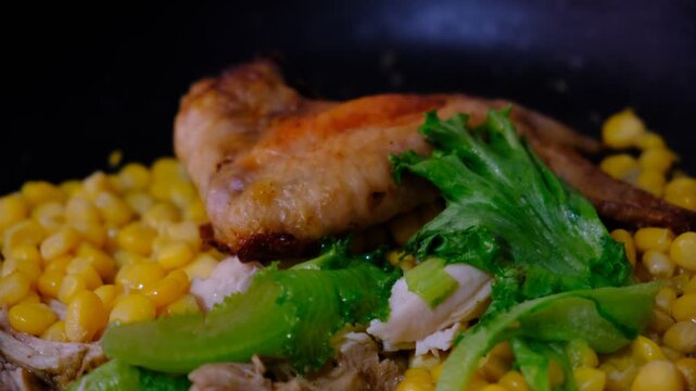 Sizzling chicken and vegetables in a pan: juicy corn, fresh lettuce leaves, and crispy Buffalo Chicken Wings &mdash; a hearty and flavorful meal.