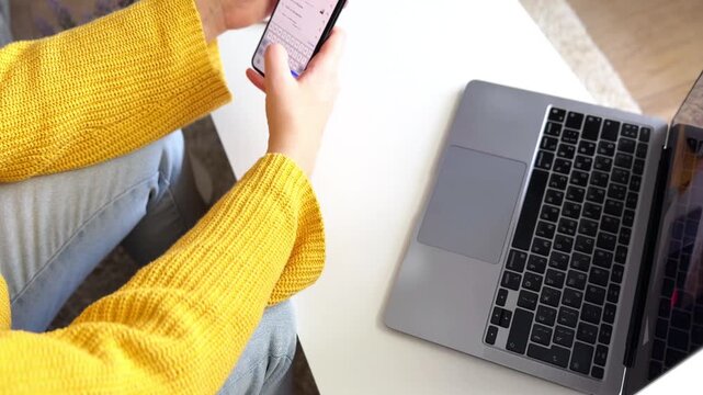 This video footage showcases a person holding a smartphone in one hand while sitting at a desk. A notepad and pen are visible, creating a productive atmosphere. Ideal for workspace themes.