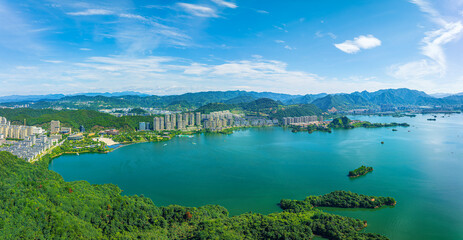 Obraz premium Panoramic aerial view of Qiandao Lake with lush green islands and modern lakeside city buildings in Hangzhou, China.