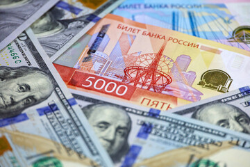 Obraz premium Russian rubles banknote on background of US dollars. Concept of exchange rate, american sanctions against Russia