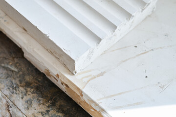 Close up of white moulded plaster decorative trim with stepped profile on wooden surface for interior design and construction detail. Manufacture and construction of moulds  © dannyburn