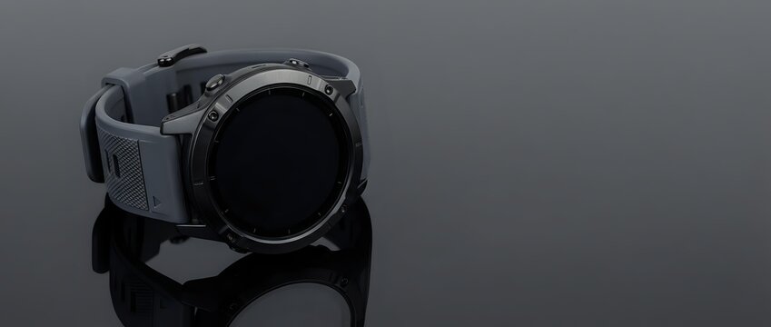Modern black smartwatch with digital display and silicone strap on reflective surface for technology and wearable device concepts.