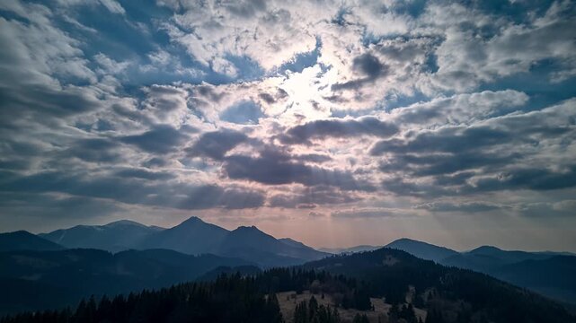 Aerial Hyperlapse of Sun Rays Breaking Through Clouds Over Mountain 