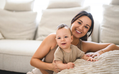 Fototapeta premium Happy baby boy in living room at home with his beautiful mother