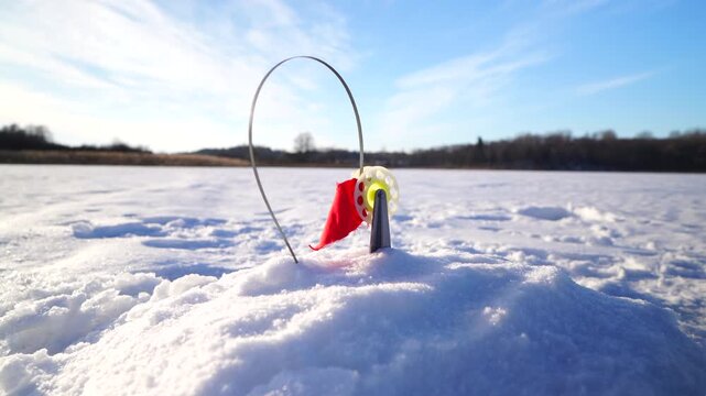 Ice fishing on frozen lake. Zherlitsa gear for winter fishing for predatory fish. Catching fish in a hole in ice on frozen river. Winter fishing. Jigging with Small jigging rod. Winter landscape with 