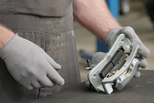 Repair of the car's braking system.Rear right brake caliper.The car mechanic visually checks the serviceability of the new brake caliper before installing it on the steering knuckle of the wheel.
