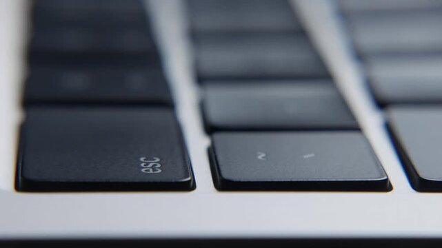 Hands typing on a laptop keyboard and pressing the Esc key during computer work, close view of fingers interacting with the controls. Digital workflow, user interaction.
