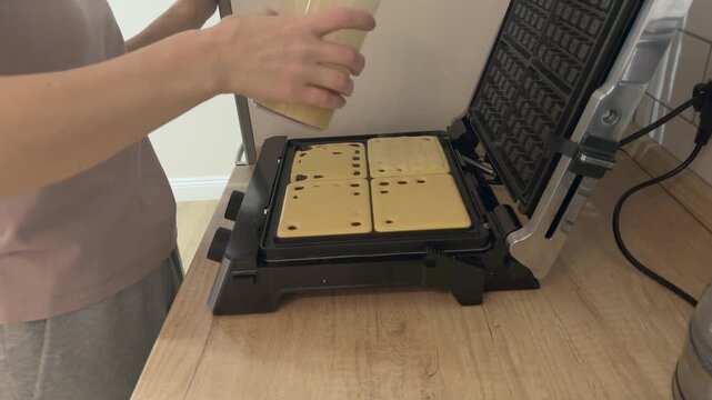 Pouring batter from cup into waffle maker cells Homemade breakfast cooking process baking sweet waffles preparation
