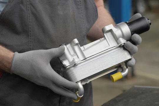 Car service.Auto parts. Oil cooler.Close-up. An auto mechanic prepares the installation of a new oil cooler.Monitoring the serviceability and integrity of a new spare part.