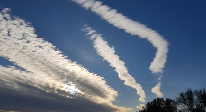 Airplane vapor trails and wispy clouds over a blue sky, illustrating atmospheric pollution and aviation carbon emissions for World Environment Day awareness.