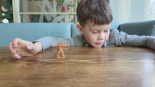 Child focused on toy soldier game creating battle scenes. Development of imagination, logic and storytelling. Suitable for education, creativity and parenting visuals.