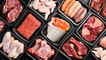 Naklejka premium Raw fresh meat and fish in Black plastic packaging trays from supermarket. Top view. Food background.