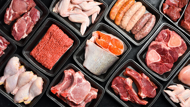 Raw fresh meat and fish in Black plastic packaging trays from supermarket. Top view. Food background.