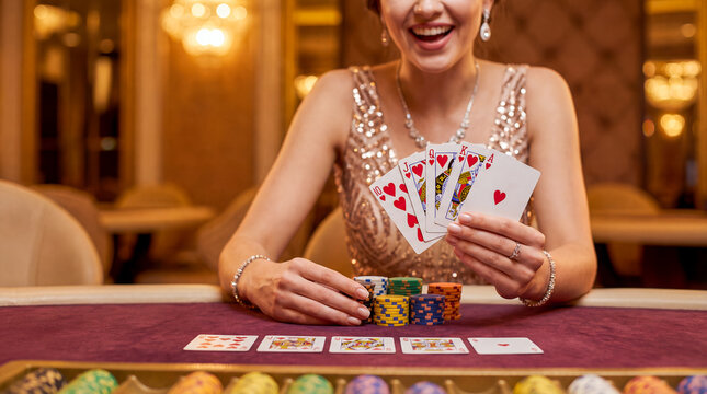 royal flush poker woman casino gambling winner cards jackpot smile shown across the table by a smiling player in a glittering dress for casino branding winner campaigns gaming ads and luxury promos