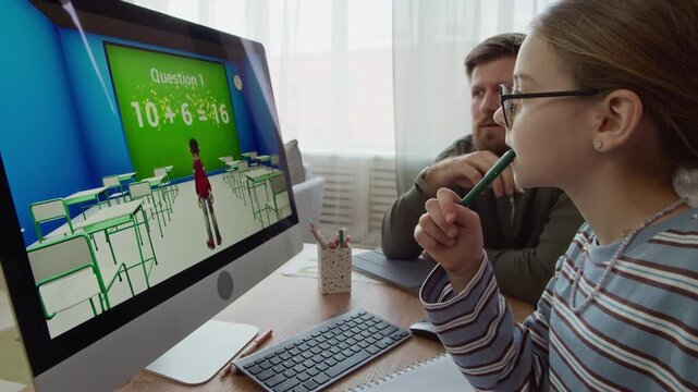 Side view of excited Caucasian gen Alpha girl solving Math exercise in computer game with father sitting at table while studying together at home