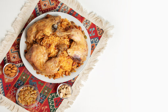 top view of chicken kabsa with nuts and raisins on woven textile