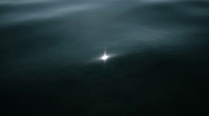 Fototapeta premium Single sun glint sparkling on dark deep water surface
