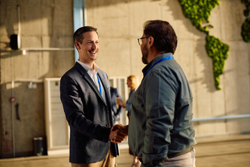 Happy businessmen greeting each other after seminar at convention center. © Drazen