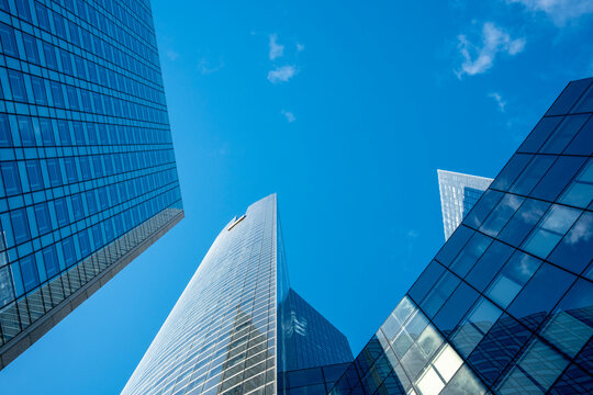 Blue perspective of a skyscraper architecture where business finance meets urban glass looking upward in Paris La Defense with clear sky