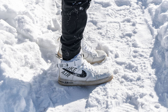 Sharkan, Russia - March 06 2022: Person stands on snowy surface wearing Nike Air Force 1 high sneakers. Snow is bright and covers ground in clear winter weather
