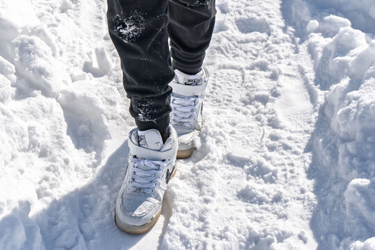 Sharkan, Russia - March 06 2022: Person stands on snowy surface wearing Nike Air Force 1 high sneakers. Snow is bright and covers ground in clear winter weather