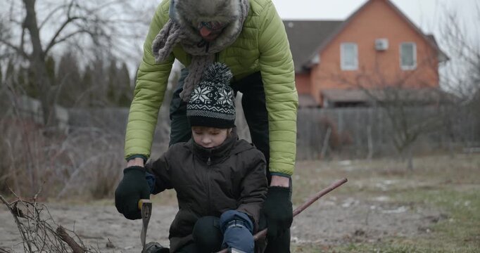 Men with kid cut branches in backyard and stockpile firewood in shed for winter. 4K 10-bit