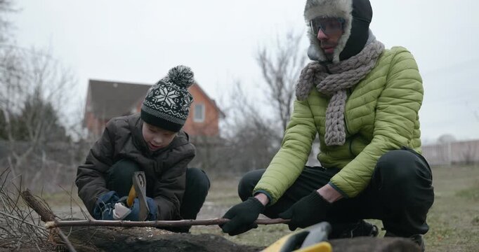 Men with kid cut branches in backyard and stockpile firewood in shed for winter. 4K 10-bit