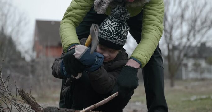 Men with kid cut branches in backyard and stockpile firewood in shed for winter. 4K 10-bit