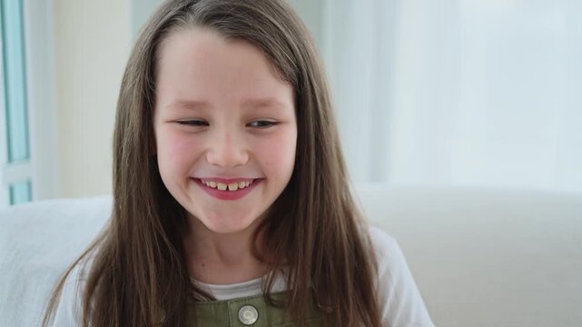 Happy girl at home. Smiling cute little brown haired Caucasian girl looking at camera. Portrait of happy female child at home. Smiling face of 10 year old girl looking at camera