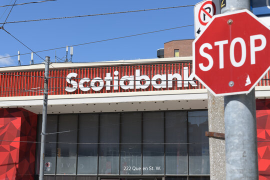 defocused stop sign and exterior building facade and sign of Scotiabank, a bank branch, located here at 222 Queen St W, Toronto