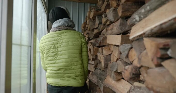Men with kid cut branches in backyard and stockpile firewood in shed for winter. 4K 10-bit