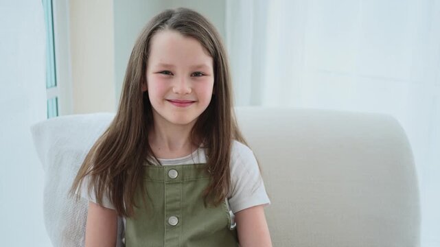 Happy girl at home. Smiling cute little brown haired Caucasian girl looking at camera. Portrait of happy female child at home. Smiling face of 10 year old girl looking at camera