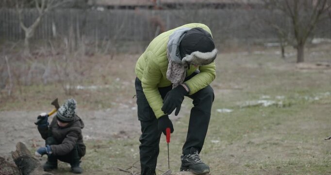 Men with kid cut branches in backyard and stockpile firewood in shed for winter. 4K 10-bit