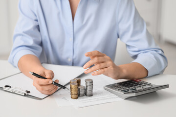 Fototapeta premium Businesswoman with stacks of coins at table in office, closeup. Tax concept