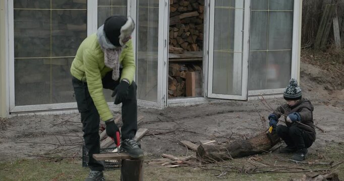 Men with kid cut branches in backyard and stockpile firewood in shed for winter. 4K 10-bit