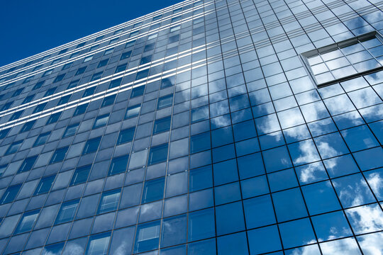 Sky clouds reflection on glass windows forms a modern architecture building facade pattern with corporate mood and clean urban design texture