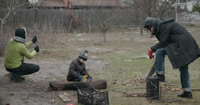 Men with kid cut branches in backyard and stockpile firewood in shed for winter. 4K 10-bit
