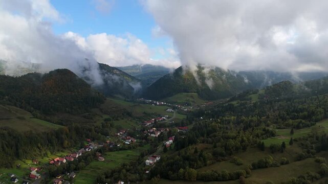 Aerial view of mountain village in green valley under cloudy sky