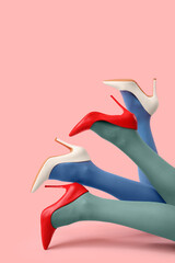 Legs of women in tights with high heels on pink background