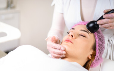 Obraz premium Young woman receiving treatment in cosmetology clinic. Cosmetology skin care. Aesthetic facial treatment Concept.