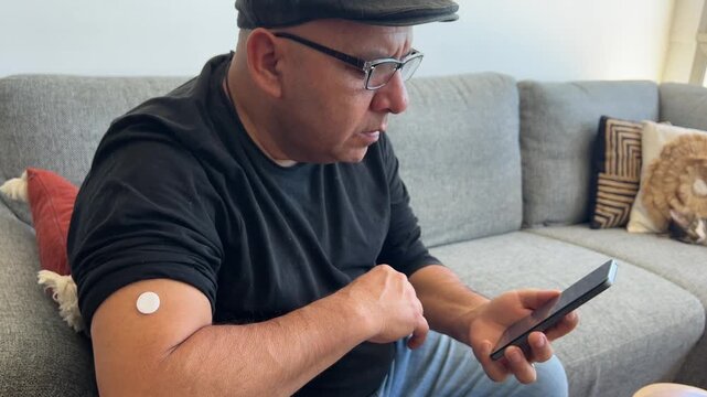 Hombre revisando gluc&oacute;metro inteligente en el m&oacute;vil