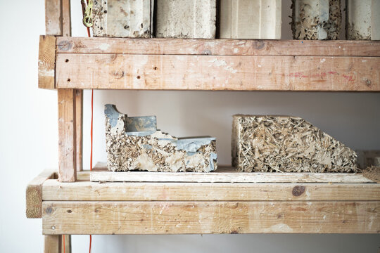 A shelf of composite textured material made from wood chips and binder on workbench. Eco wood recycling fire wood blocks for fuel and energy.