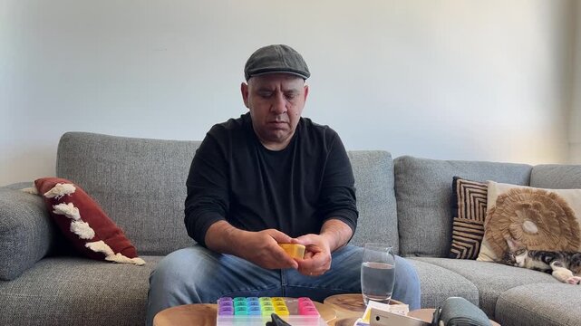 Hombre tomando pastillas del pastillero con vaso de agua