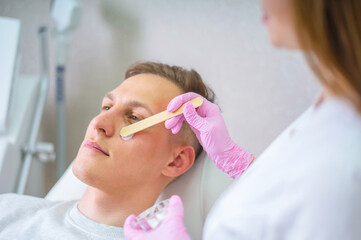 Naklejka premium Male cosmetics. Good looking man receiving face treatment at luxury spa