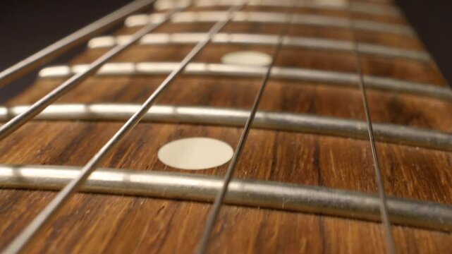 Cinematic glide across electric guitar fretboard highlighting strings frets and texture macro shot
